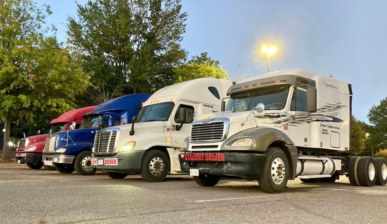 Row of CDL Class A training trucks at Carolina Trucking Academy
